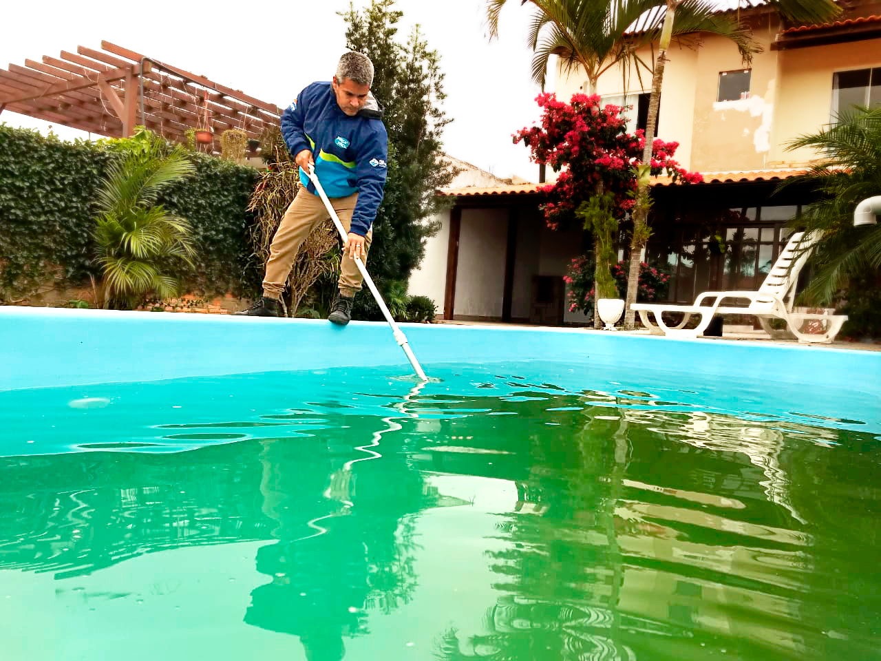 Piscineiro avaliando piscina residencial com água verde