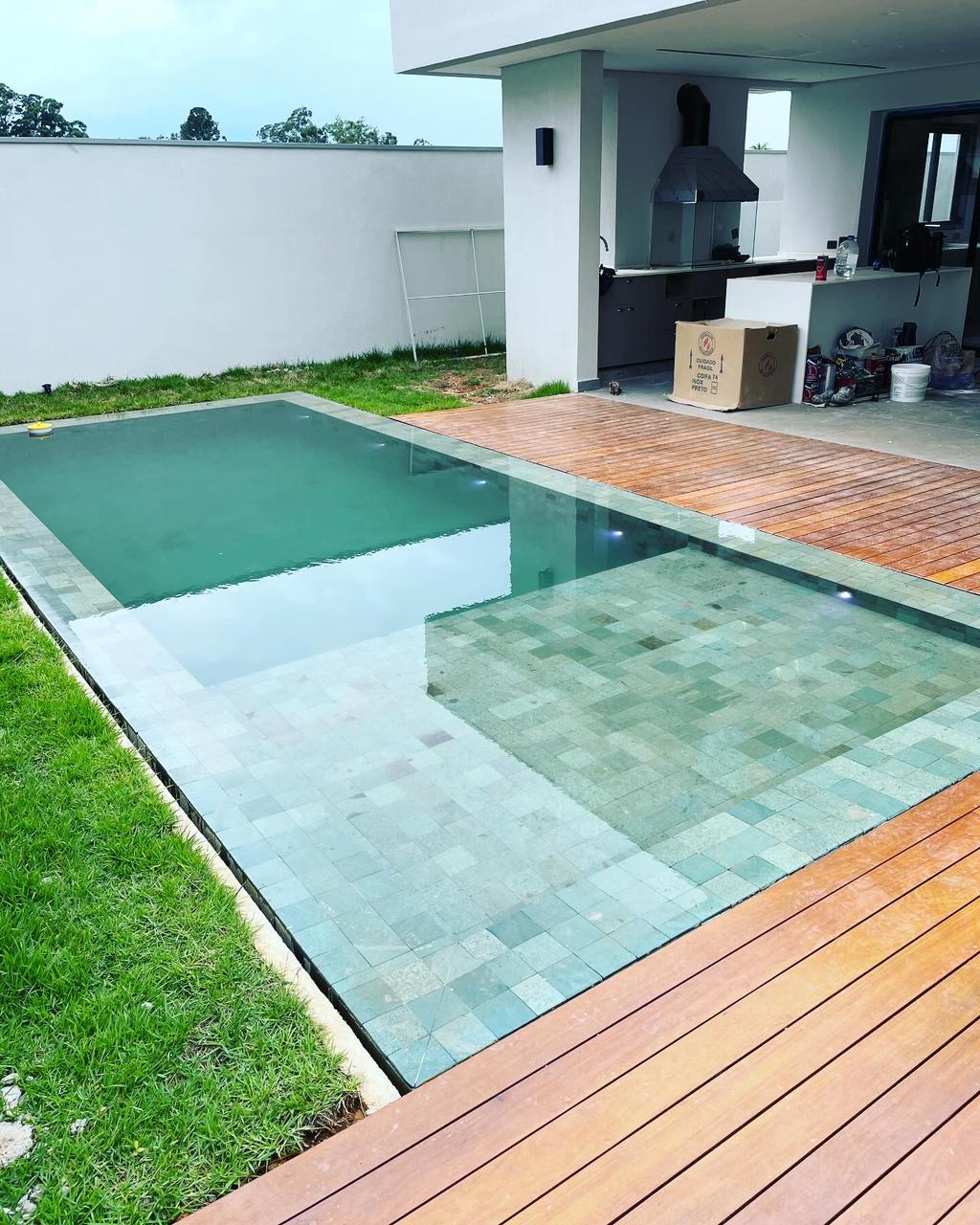 Piscina residencial de alto padrão finalizada com prainha e deck de madeira