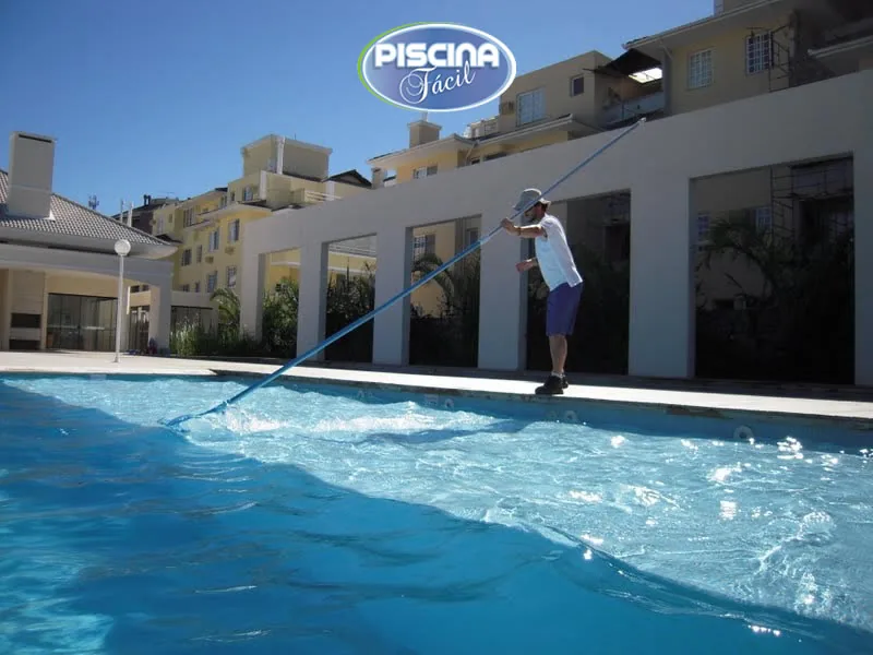 Profissional executando manutenção e limpeza de piscina coletiva